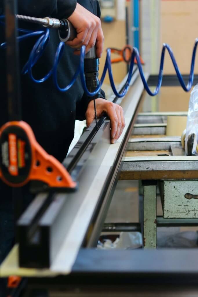 Artigiano lavora su un serramento in legno durante le fasi di montaggio e installazione.