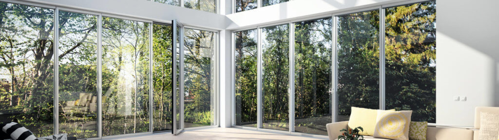Panoramica su serramenti in alluminio con grande vetrata e vista su un giardino.